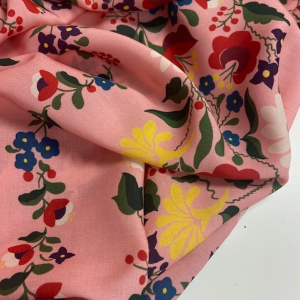 pink floral fabric with hints of yellow, blue and green flower heads and leaves.